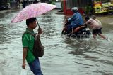 Dua orang anak mendorong sepeda motor yang mogok akibat memaksakan untuk melintasi banjir di Jalan Raya Pelni, Taman Duta, Depok, Jawa Barat, Kamis (9/1/2025). Banjir di kawasan tersebut terus berulang setelah hujan deras, dan menyebabkan meluapnya air Sungai Kalibaru sehingga akses jalan tergenang air setinggi 30-60 cm. ANTARA FOTO/Yulius Satria Wijaya/foc.