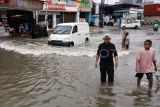 Warga melintasi banjir di Jalan Raya Pelni, Taman Duta, Depok, Jawa Barat, Kamis (9/1/2025). Banjir di kawasan tersebut terus berulang setelah hujan deras, dan menyebabkan meluapnya air Sungai Kalibaru sehingga akses jalan tergenang air setinggi 30-60 cm. ANTARA FOTO/Yulius Satria Wijaya/foc.