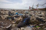 Warga melihat kondisi pantai yang penuh dengan tumpukan sampah di Pantai Dadap, Indramayu, Jawa Barat, Minggu (12/1/2025). Sampah yang sebagian besar dari limbah rumah tangga dan plastik tersebut terseret arus dan menumpuk di pantai sehingga mengganggu aktivitas nelayan. ANTARA FOTO/Dedhez Anggara/nym.