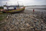 Warga melihat kondisi pantai yang penuh dengan tumpukan sampah di Pantai Dadap, Indramayu, Jawa Barat, Minggu (12/1/2025). Sampah yang sebagian besar dari limbah rumah tangga dan plastik tersebut terseret arus dan menumpuk di pantai sehingga mengganggu aktivitas nelayan. ANTARA FOTO/Dedhez Anggara/nym.