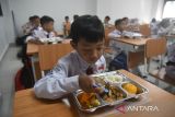 Sejumlah siswa menyantap makan bergizi gratis di SDN Cimahpar 3, Kota Bogor, Jawa Barat, Senin (13/01/2025). Badan Komunikasi Nasional Desa se-Indonesia (BKNDI) bekerja sama dengan sejumlah perusahaan swasta nasional yang mendukung program Makan Bergizi Gratis (MBG) memulai uji coba pemberian makanan bergizi gratis sebanyak 1500 porsi paket yang dibagikan untuk lima Sekolah Dasar Negeri di wilayah Cimahpar, Kota Bogor. (ANTARA FOTO/Arif Firmansyah).