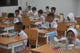 Sejumlah siswa menyantap makan bergizi gratis di SDN Cimahpar 3, Kota Bogor, Jawa Barat, Senin (13/01/2025). Badan Komunikasi Nasional Desa se-Indonesia (BKNDI) bekerja sama dengan sejumlah perusahaan swasta nasional yang mendukung program Makan Bergizi Gratis (MBG) memulai uji coba pemberian makanan bergizi gratis sebanyak 1500 porsi paket yang dibagikan untuk lima Sekolah Dasar Negeri di wilayah Cimahpar, Kota Bogor. (ANTARA FOTO/Arif Firmansyah).