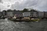 Nelayan dengan perahunya melintas di samping pagar laut yang terpasang di kawasan pesisir Tarumajaya, Kabupaten Bekasi, Jawa Barat, Selasa (14/1/2025). Menurut nelayan setempat pemasangan pagar laut yang membentang sepanjang 2 km itu mengganggu lalu lintas kapal kecil dan berpotensi merusak ekosistem laut karena adanya pengerukan tanah. ANTARA FOTO/Fakhri Hermansyah/tom.