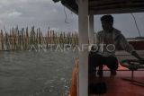 Pengemudi perahu mengamati pagar laut yang terpasang di kawasan pesisir Tarumajaya, Kabupaten Bekasi, Jawa Barat, Selasa (14/1/2025). Menurut nelayan setempat pemasangan pagar laut yang membentang sepanjang 2 km itu mengganggu lalu lintas kapal kecil dan berpotensi merusak ekosistem laut karena adanya pengerukan tanah. ANTARA FOTO/Fakhri Hermansyah/tom.