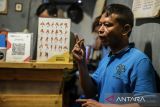 Penyandang disabilitas tunarungu dan tunawicara melayani pembeli menggunakan bahasa isyarat di Kedai Kopi Joy, Kota Serang, Banten, Selasa (14/1/2025). Kedai kopi yang memberdayakan empat penyandang disabilitas tersebut sebagai sarana ruang inkulsi bagi komunitas disabilitas guna mengembangkan kepercayaan diri maupun keahlian dalam wirausaha. ANTARA FOTO/Muhammad Bagus Khoirunas/gp