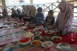 Sejumlah anak yatim dan anak keluarga miskin menyantap makanan saat perayaan tradisi Kenduri Laut di Tempat Pendaratan Ikan (TPI) desa Lhoksudu, kecamatan Leupung, kabupaten Aceh Besar, Aceh,  Kamis (16/1/2025). Perayaan Kenduri Laot atau Kenduri Laut yang digelar nelayan sekali dalam setahun  itu sebagai bentuk rasa syukur atas limpahan rezeki dari Yang Maha Kuasa dan hingga saat ini  tetap dilestarikan warga pesisir sebagai budaya leluhur  dan kearifan lokal masyarakat pesisir di Aceh. ANTARA FOTO/Ampelsa.