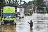 Petugas memandu jalannya arus lalu lintas saat banjir menggenangi Jalan Lintas Sumatera, Merlung, Jambi, Senin (20/1/2025). Arus lalu lintas di jalan nasional yang sempat lumpuh total selama lebih dari 24 jam sejak Minggu (19/1/2025) sore akibat banjir setinggi 150 sentimeter dan terjebaknya dua buah mobil di tengah-tengah banjir itu sudah berhasil dilalui dengan sistem buka tutup. ANTARA FOTO/Wahdi Septiawan/YU