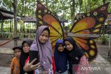 Sejumlah anak berswafoto dengan latar belakang hiasan kupu-kupu di Hutan Jati Raya Sindang Asih, Kabupaten Tangerang, Banten, Sabtu (25/1/2025). Destinasi wisata alam dengan memanfaatkan hutan pohon jati yang dikelola swadaya oleh warga desa setempat  tersebut menyediakan wahana permainan anak, tempat tidur gantung, motor ATV dan spot foto. ANTARA FOTO/Putra M. Akbar/gp