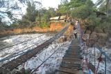 Pengunjung menyeberangi Jembatan Cinta di kawasan objek wisata Pantai Sungai Suci, Kabupaten Bengkulu Tengah, Bengkulu, Senin (27/1/2025). Objek wisata yang berjarak 1,5 kilometer dari Kota Bengkulu tersebut menjadi destinasi favorit warga lokal dan luar Bengkulu untuk menikmati libur panjang Isra Miraj dan Tahun Baru Imlek. ANTARA FOTO/Muhammad Izfaldi