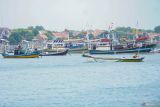 Warga melintas di sekitar kapal milik nelayan yang tak melaut menggunakan sampan di pesisir selatan Pulau Gili Ketapang, Kabupaten Probolinggo, Jawa Timur, Senin (3/2/2025). Sejumlah nelayan di kawasan tersebut memilih tidak melaut sejak 15 hari terakhir dikarenakan cuaca buruk gelombang tinggi dan angin kencang di perairan Laut Jawa. ANTARA Jatim/Irfan Sumanjaya/mas.
