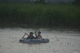 Dua anak menaiki perahu karet di lahan pertanian yang terendam banjir di Desa Kendit, Situbondo, Jawa Timur, Kamis (6/2/2025). Dinas Pertanian dan Ketahanan Pangan Kabupaten Situbondo mencatat sekitar 684,5 hektare lahan pertanian di lima kecamatan terendam banjir. Antara Jatim/Seno/um 