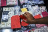 Petugas kepolisian menata barang bukti uang palsu sebelum pengungkapan peredaran uang palsu di Mapolda Banten, Kota Serang, Banten, Kamis (6/2/2025). Polda Banten berhasil mengamankan sebanyak 14 tersangka pengedar sekaligus produksi uang palsu yang beraksi di wilayah Tangerang dengan barang bukti berupa mesin cetak, uang palsu sebanyak 2037 lembar dengan rincian pecahan Rp100.000 sebanyak 1600 lembar, pecahan Rp50.000 sebanyak 437 lembar, serta mata uang asing Real Brasil sebanyak 200 lembar, dan 1034 lembar mata uang dolar Amerika Serikat. ANTARA FOTO/Muhammad Bagus Khoirunas/gp