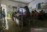 Sejumlah siswa mengikuti kegiatan belajar mengajar di salah satu ruang kelas yang terendam banjir di SD Negeri Eretan, Tirtayasa, Kabupaten Serang, Banten, Sabtu (8/2/2025). Pihak sekolah menyebutkan sejak enam tahun terakhir sekolah tersebut menjadi langganan banjir akibat luapan saluran irigasi yang ada di sekitar area sekolah dengan ketinggian air sekitar 25-30 centimeter dan merendam sebanyak enam ruang kelas, satu ruang guru, dan dua gudang sekolah. ANTARA FOTO/Angga Budhiyanto/gp