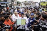 Menteri Agraria dan Tata Ruang (ATR)/Kepala Badan Pertanahan Nasional (BPN) Nusron Wahid menunjukkan sertifikat usai meninjau salah satu lahan sengketa yang sudah digusur di kawasan Tambun Selatan, Kabupaten Bekasi, Jawa Barat, Jumat (7/2/2025). Nusron meninjau sejumlah titik di kawasan tersebut yang lahannya disengketakan karena polemik jual-beli dari pemilik induk lahan. ANTARA FOTO/Dhemas Reviyanto/Spt.