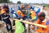 Sejumlah pekerja memasang rel saat pemasangan jembatan baru kereta api di Desa Jambean, Kabupaten Kediri, Jawa Timur, Senin (10/2/2025). Direktorat Jenderal Perkeretaapian Kementerian Perhubungan mengganti jembatan kereta api sepanjang 32 meter dengan anggaran sebesar Rp 24miliar berlokasi di petak antara Stasiun Kras dan Stasiun Ngadiluwih yang merupakan kawasan rawan banjir sebagai upaya meningkatkan kenyamanan dan keamanan perjalanan kereta api. Antara Jatim/Prasetia Fauzani/um