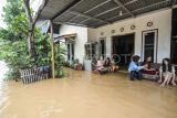 Warga berkumpul di teras rumah yang terendam banjir di Kenali Asam, Jambi, Minggu (23/2/2025). Puluhan rumah dan sekolah terendam banjir akibat luapan Sungai Kenali Asam setelah diguyur hujan lebat pada Minggu (23/2/2025) dini hari. ANTARA FOTO/Wahdi Septiawan/agr