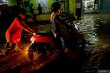 Warga membantu mendorong sepeda motor yang mogok saat melintasi jalan raya terendam banjir di simpang empat Cuwiri, Tulungagung, Jawa Timur, Rabu (26/2/2025). Banjir dpicu hujan tanggul jebol pascaturun hujan deras itu merendam ratusan rumah warga, area persawahan hingga akses jalan raya terendam air hingga lutut orang dewasa. ANTARA Jatim/Destyan Sujarwoko/mas.
