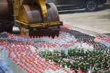 Alat berat memusnahkan barang bukti minuman beralkohol (minol) dengan cara dilindas di Mapolres Kabupaten Jombang, Jawa Timur, Jumat (28/2/2025). Sebanyak 5.122 botol minuman beralkohol berbagai jenis hasil ungkap selama 15 hari dengan 25 orang tersangka dimusnahkan Polres Jombang menjelang Ramadhan. ANTARA Jatim/Syaiful Arif/mas.
