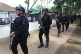 Anggota Brimob Polda Jawa Timur berjaga di sekitar lokasi saat penggeladahan rumah oleh Badan Narkotika Nasional Provinsi (BNNP) Jawa Timur di Dusun Rabesan Barat, Desa Parseh, Kecamatan Socah, Bangkalan, Jawa Timur, Senin (3/3/2025). Penggeledahan yang dilakukan BNNP Jatim di rumah salah satu daftar pencarian orang (DPO) berinisial MLS tersebut guna mencari bukti-bukti tambahan terkait kasus peredaran narkoba jenis sabu seberat 14,86 kilogram yang didapatkan dari tersangka AM usai ditangkap pada Rabu (19/2). ANTARA Jatim/Moch Asim.