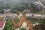 Foto udara warga menyaksikan kondisi jalan lintas Sumatera yang amblas di Desa Sirih Sekapur, Bungo, Jambi, Rabu (5/3/2025). Jalan nasional yang menghubungkan Provinsi Jambi dengan Sumatera Barat yang amblas pada Minggu (2/3) akibat hujan deras itu hingga Rabu (5/3) pagi masih belum bisa dilintasi, sementara Balai Pelaksana Jalan Nasional (BPJN) Jambi masih berupaya membangun jembatan darurat. ANTARA FOTO/Wahdi Septiawan/nym.