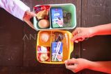 Seorang siswa menunjukkan menu makan bergizi gratis bulan Ramadhan di SDN Slipi 15, Jakarta, Kamis (6/3/2025). Kepala Badan Gizi Nasional (BGN) Dadan Hindayana menyatakan pelaksanaan makan bergizi gratis selama bulan Ramadhan menggunakan makanan yang tahan lama seperti susu, telur, buah, kurma, dan kue kering sehingga dapat dibawa pulang untuk berbuka puasa. ANTARA FOTO/Sulthony Hasanuddin/Spt.