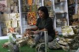 Perajin Siti Mudrikah mengemas cenderamata kain bercorak daun ecoprint hasil produksinya di Sanggar Kreasi Mamalya, Malang, Jawa Timur, Sabtu (8/3/2025). Dalam sebulan lebih dari seribu buah produk bercorak daun ecoprint  berbagai jenis antara lain kain, kemeja, sepatu, sofa dan toples kue lebaran mampu terjual ke mancanegara dan berbagai kota di Indonesia melalui media sosial dengan harga Rp15 ribu hingga Rp5 juta menurut jenis produknya. ANTARA Jatim/Ari Bowo Sucipto/mas.