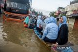 Pekerja menggunakan jasa ojek perahu untuk melintasi banjir di ruas Jalan Raya Dayeuhkolot, Kabupaten Bandung, Jawa Barat, Sabtu (8/3/2025). Sebanyak 60 pekerja pabrik di kawasan tersebut terpaksa menggunakan jasa ojek perahu dengan membayar Rp5.000 hingga Rp10.000 per orang untuk melintas karena terdampak banjir luapan Sungai Citarum yang merendam jalan dan membuat sejumlah kendaraan mogok. ANTARA FOTO/Novrian Arbi/agr
