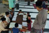 Ustadz mengawasi santri cilik membaca alquran bersama di serambi Masjid Kasepuhan Pardikan Majan, Tulungagung, Jawa Timur, Selasa (11/3/2025). Sebanyak 40 santri yang dibagi ke dalam tiga kelompok usia dini dilatih membaca Al Quran masing-masing satu juz per hari hingga para santri fasih dan berhasil khatam di akhir Ramadhan. Antara Jatim/Destyan Sujarwoko/um