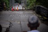 Warga melintasi Jembatan Cicangor yang ambles di Pangkalan, Karawang, Jawa Barat. Jembatan penghubung jalan provinsi yang menjadi akses utama dari Loji menuju Karawang kota atau sebaliknya itu amblas karena terkikis derasnya aliran sungai, akibatnya tidak bisa dilalui kendaraan roda empat maupun roda dua. ANTARA FOTO/Bayu Pratama S/rwa.