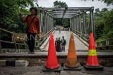 Warga melintasi Jembatan Cicangor yang ambles di Pangkalan, Karawang, Jawa Barat. Jembatan penghubung jalan provinsi yang menjadi akses utama dari Loji menuju Karawang kota atau sebaliknya itu amblas karena terkikis derasnya aliran sungai, akibatnya tidak bisa dilalui kendaraan roda empat maupun roda dua. ANTARA FOTO/Bayu Pratama S/rwa.