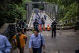 Warga melintasi Jembatan Cicangor yang ambles di Pangkalan, Karawang, Jawa Barat. Jembatan penghubung jalan provinsi yang menjadi akses utama dari Loji menuju Karawang kota atau sebaliknya itu amblas karena terkikis derasnya aliran sungai, akibatnya tidak bisa dilalui kendaraan roda empat maupun roda dua. ANTARA FOTO/Bayu Pratama S/rwa.