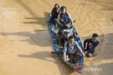 Warga menggunakan perahu melintasi banjir di Dayeuhkolot, Kabupaten Bandung, Jawa Barat, Minggu (16/3/2025). Banjir setinggi 30 sentimeter hingga 2 meter akibat luapan air Sungai Citarum saat intensitas curah hujan tinggi kembali merendam tiga kecamatan yakni Bojongsoang, Baleendah, dan Dayeuhkolot di Bandung Selatan. ANTARA FOTO/Novrian Arbi/agr