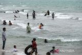 Sejumlah wisatawan bermain air saat gelombang menerjang kawasan Pantai Anyer di Kabupaten Serang, Banten, Selasa (1/4/2025). Badan Meteorologi, Klimatologi dan Geofisika (BMKG) mengeluarkan peringatan dini untuk mewaspadai gelombang tinggi laut Banten yang mencapai 1,25 hingga 2,5 meter meliputi perairan Selat Sunda di sepanjang Pantai Anyer, Carita, dan Tanjung Lesung yang terjadi selama libur Lebaran 2025. ANTARA FOTO/Muhammad Bagus Khoirunas/gp