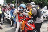 Kapolres Jombang AKBP Ardi Kurniawan memakaikan kacamata dalam aksi simpatik di jalan raya Bandar Kedungmulyo, Kabupaten Jombang, Jawa Timur, Minggu (6/4/2025). Aksi simpatik pembagian helm dan kacamata gratis itu merupakan bentuk kepedulian Polres Jombang terhadap keselamatan pengendara sepeda motor, dan mendukung keselamatan lalu lintas selama arus balik Lebaran 2025. Antara Jatim/Syaiful Arif/um