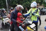 Polisi memasangkan kacamata gratis untuk anak-anak di jalan raya Bandar Kedungmulyo, Kabupaten Jombang, Jawa Timur, Minggu (6/4/2025). Aksi simpatik pembagian helm dan kacamata gratis itu merupakan bentuk kepedulian Polres Jombang terhadap keselamatan pengendara sepeda motor, dan mendukung keselamatan lalu lintas selama arus balik Lebaran 2025. Antara Jatim/Syaiful Arif/um