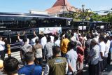 Sejumlah pejabat daerah dan warga melambaikan tangan kepada pemilir yang berada di dalam bus saat pemberangkatan Balik Gratis Bareng Pemkot Madiun di Kota Madiun, Jawa Timur, Senin (7/4/2025). Pemkot Madiun memfasilitasi milir gratis bagi sekitar 300 orang pemilir setelah berlebaran di Madiun untuk kembali  ke kota tujuan Jakarta dan Surabaya menggunakan enam unit bus. Antara Jatim/Siswowidodo/mas.