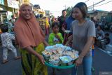 Warga membawa nampan berisi beraneka hidangan gratis yang didapat saat Lebaran Ketupat di Sukolilo Baru, Surabaya, Jawa Timur, Senin (7/4/2025). Tradisi yang dirayakan sepekan setelah Hari Raya Idul Fitri di kawasan pemukiman di Pantai Kenjeran itu digelar dengan membagikan berbagai hidangan secara gratis kepada warga sekitar dan sebagai ajang untuk bersilaturahim. ANTARA Jatim/Didik Suhartono/mas.