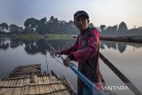 Pekerja menarik rakit eretan saat menyeberangi sungai Citarum di Batujajar, Kabupaten Bandung Barat, Jawa Barat, Rabu (9/4/2025). Jasa penyeberangan rakit eretan dengan tarif Rp1.000 - Rp5.000 tersebut mayoritas digunakan para buruh pabrik dan warga sekitar sebagai alternatif transportasi untuk mempersingkat waktu serta jarak tempuh. ANTARA FOTO/Abdan Syakura/agr