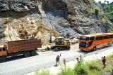 Petugas mengerahkan alat berat dan dump truck untuk menormalisasi material longsor di jalan raya JLS Trenggalek-Tulungagung Km10+800 Desa Keboireng, Tulungagung, Jawa Timur, Minggu (13/4/2025). Akses pesisir yang menjadi penghubung sejumlah kawasan wisata pantai di Trenggalek dan Tulungagung itu sempat ditutup total akibat dinding tebing setinggi 20 meter dan lebar 10 meter di sisi JLS dekat perbatasan Trenggalek-Tulungagung ambrol/longsor pada Minggu (13/4/2025) dini hari sekitar pukul 00.15 WIB sehingga menutup 2/3 badan jalan setempat. JANTARA Jatim/Destyan Sujarwoko/mas.