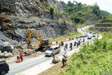 Kendaraan mengantri giliran melintasi titik longsor di jalan raya JLS Trenggalek-Tulungagung Km10+800 Desa Keboireng, Tulungagung, Jawa Timur, Minggu (13/4/2025). Akses pesisir yang menjadi penghubung sejumlah kawasan wisata pantai di Trenggalek dan Tulungagung itu sempat ditutup total akibat dinding tebing setinggi 20 meter dan lebar 10 meter di sisi JLS dekat perbatasan Trenggalek-Tulungagung ambrol/longsor pada Minggu (13/4/2025) dini hari sekitar pukul 00.15 WIB sehingga menutup 2/3 badan jalan setempat. JANTARA Jatim/Destyan Sujarwoko/mas.