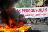 Pedagang kaki lima pemilik bangunan liar berunjukrasa dengan membakar ban dan membentangkan spanduk menolak penggusuran lapak PKL di Jalan Pepelegi, Sidoarjo, Jawa Timur, Senin (14/4/2025). Aksi tersebut dilakukan untuk mempertahankan bangunan karena menganggapnya sebagai sumber penghidupan dan mendesak pemerintah setempat untuk dialog yang bisa menghasilkan solusi bersama. Antara Jatim/Umarul Faruq