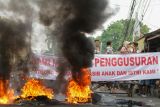 Pedagang kaki lima pemilik bangunan liar berunjukrasa dengan membakar ban dan membentangkan spanduk menolak penggusuran lapak PKL di Jalan Pepelegi, Sidoarjo, Jawa Timur, Senin (14/4/2025). Aksi tersebut dilakukan untuk mempertahankan bangunan karena menganggapnya sebagai sumber penghidupan dan mendesak pemerintah setempat untuk dialog yang bisa menghasilkan solusi bersama. Antara Jatim/Umarul Faruq