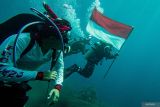 Pembawa Bendera Merah Putih Lettu Laut (PM) R. Farras Kurniawan (kanan) bersama Pembawa Bendera Amerika Captain USMC Josh Cambers (kedua kiri) melakukan penyelaman untuk memasang Prasasti dan Pengibaran Bendera Indonesia dan Amerika di area Kapal karam Amerika USAT Liberty di Perairan Tulamben, Desa Tulamben, Kubu, Bali, Kamis (17/4/2025). Penyelaman dan pemasangan prasasti yang dilaksanakan oleh Naval Historical Diver Dinas Sejarah AL dan Kedutaan Besar Amerika untuk Indonesia tersebut digelar sebagai penghormatan terhadap situs sejarah USAT Liberty, pengingat akan kerja sama antar bangsa, serta pelestarian warisan budaya bawah laut di Indonesia. ANTARA FOTO/Muhammad Adimaja/wsj.