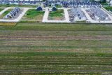 Foto udara kompleks perumahan yang berdiri di dekat area persawahan kawasan Candi, Sidoarjo, Jawa Timur, Minggu (20/4/2025). Badan Pusat Statistik Provinsi Jawa Timur mencatat luas panen padi pada tahun 2024 mencapai 1,62 juta hektare, atau mengalami penurunan sebesar 0,08 juta hektare dibandingkan 2023 yang sebesar 1,70 juta hektare akibat alih fungsi lahan yang terjadi. Antara Jatim/Umarul Faruq