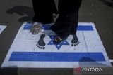 Pengunjuk rasa menginjak poster bendera Israel saat Aksi Peduli Palestina di Taman Elektrik, Kota Tangerang, Banten, Minggu (20/4/2025). Mereka mendukung kemerdekaan Palestina sekaligus mengecam pembantaian warga Gaza oleh Israel. ANTARA FOTO/Putra M. Akbar/gp