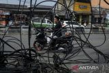 Pengendara sepeda motor melintas di samping kabel utilitas yang semrawut di Jalan Moh. Toha, Kota Tangerang, Banten, Senin (21/4/2025). Kabel utilitas yang tidak terawat hingga menjuntai ke jalan tersebut mengganggu keindahan tata ruang kota dan berpotensi membahayakan pengguna jalan. ANTARA FOTO/Putra M. Akbar/gp