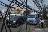 Pengendara sepeda motor melintas di samping kabel utilitas yang semrawut di Jalan Moh. Toha, Kota Tangerang, Banten, Senin (21/4/2025). Kabel utilitas yang tidak terawat hingga menjuntai ke jalan tersebut mengganggu keindahan tata ruang kota dan berpotensi membahayakan pengguna jalan. ANTARA FOTO/Putra M. Akbar/gp