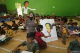 Kapolsek Plemahan AKP Bowo Wicaksono (ketiga kanan) memandu anak-anak mewarnai tokoh Kartini dan seorang polwan memainkan wayang edukasi di TK Dharmawanita Plemahan, Kabupaten Kediri, Jawa Timur, Senin (21/4/2025). Program Polisi Sahabat Anak Polsek Plemahan tersebut diisi dengan pentas wayang karton dan mewarnai tokoh Kartini guna memperingati Hari Kartini sekaligus edukasi sejak dini terkait kesetaraan dalam kesempatan mencapai cita-cita antara laki-laki dan perempuan. ANTARA Jatim/Prasetia Fauzani/mas.