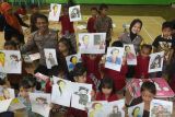 Kapolsek Plemahan AKP Bowo Wicaksono (kedua kiri) bersama anak-anak memperlihatkan gambar tokoh Kartini dan sejumlah gambar perempuan dengan berbagai profesi di TK Dharmawanita Plemahan, Kabupaten Kediri, Jawa Timur, Senin (21/4/2025). Program Polisi Sahabat Anak Polsek Plemahan tersebut diisi dengan pentas wayang karton dan mewarnai tokoh Kartini guna memperingati Hari Kartini sekaligus edukasi sejak dini terkait kesetaraan dalam kesempatan mencapai cita-cita antara laki-laki dan perempuan. ANTARA Jatim/Prasetia Fauzani/mas.