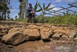 Pengendara sepeda motor melintasi jalan rusak di Desa Bojongkoneng, Ngamprah, Kabupaten Bandung Barat, Jawa Barat, Selasa (22/4/2025). Jalan poros penghubung sejumlah desa di Kecamatan Ngamprah dengan kecamatan sekitarnya rusak dan berlubang di sejumlah titik sehingga menghambat distribusi hasil pertanian dan membahayakan pengendara terutama pada malam hari. ANTARA FOTO/Abdan Syakura/agr